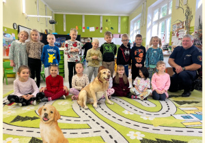 Dzieci z grupy III pozują do zdjęcia z psem i jego opiekunem